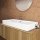 Waschtisch von Ideal Standard in seidenweißer Oberfläche, rechteckig mit Wandmontage, ausgestattet mit einem modernen Wasserhahn auf Holzuntergestell.